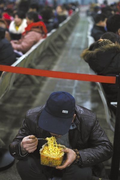 北京西站臨時(shí)候車廳，鄧軍吃著妻子泡好的方便面